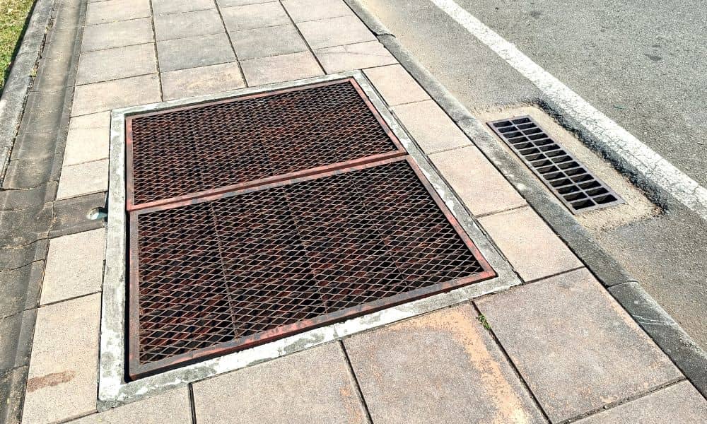 Storm sewer drain grate along a city street designed to collect and manage rainwater runoff
